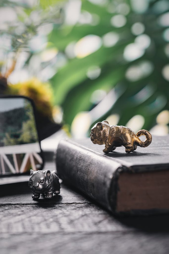 Antique book with metallic animal figurines and lush green plant background.